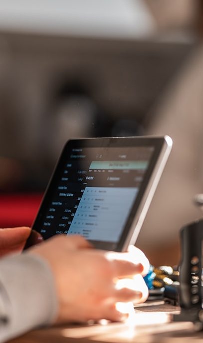 Close-up of hands holding a tablet displaying a spreadsheet or data, with soft natural light.