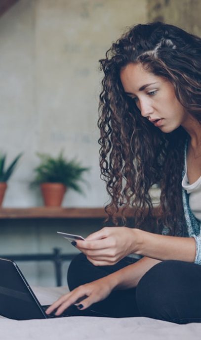 Woman making an online payment with a credit card on a laptop.