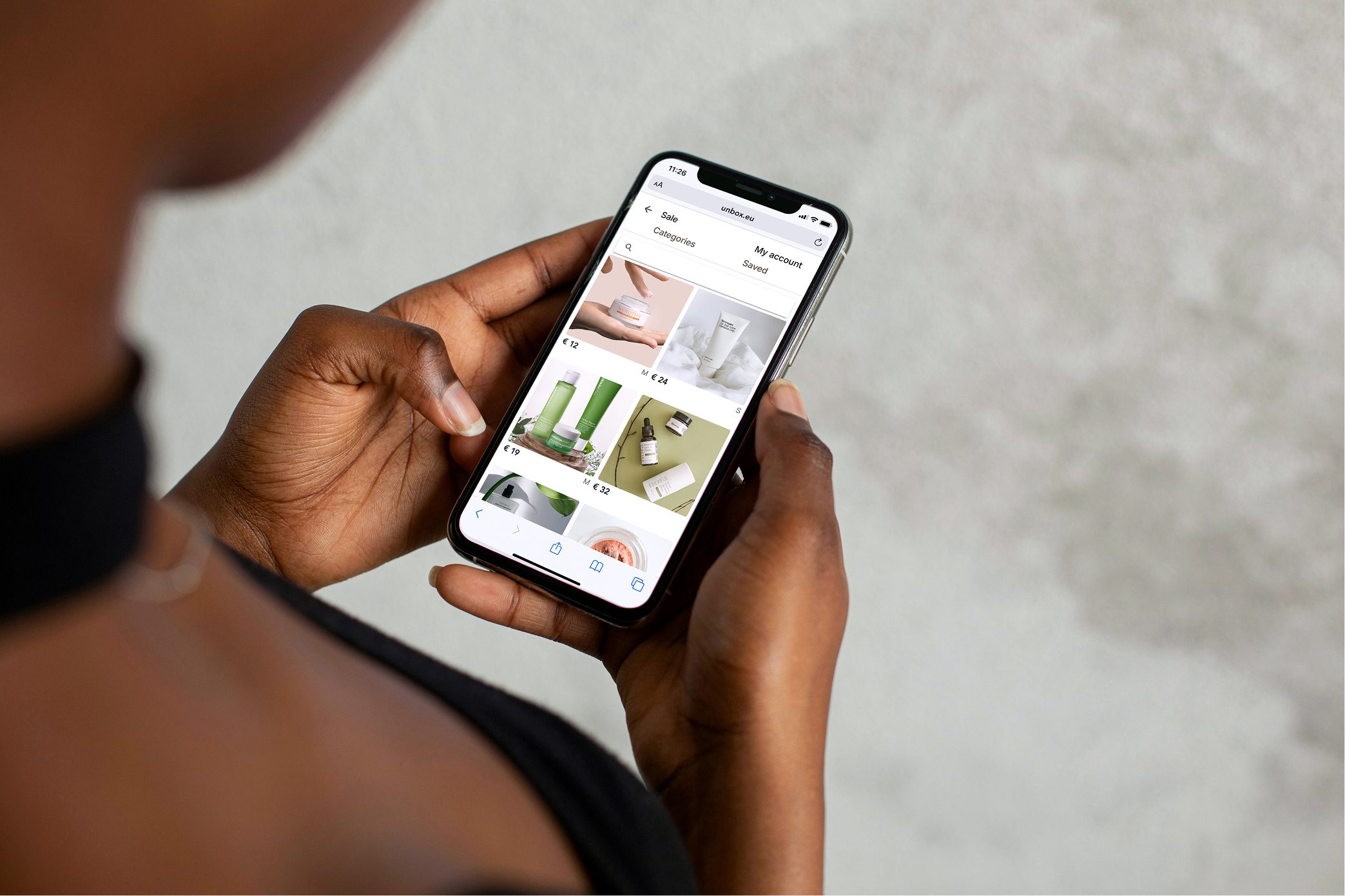 Hands holding a smartphone displaying an online store for beauty products.